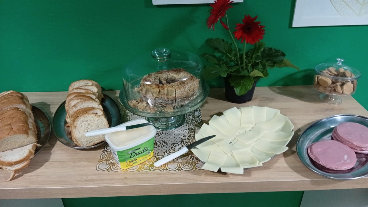 Mesa de café da manhã com pães, frios e bolo